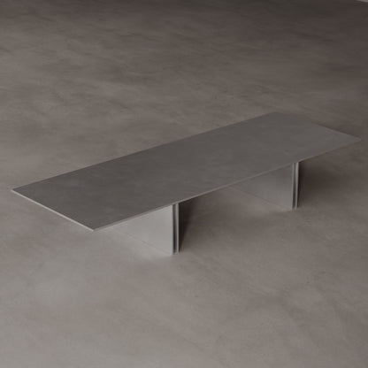 Long, stainless steel coffee table on a matching grey floor