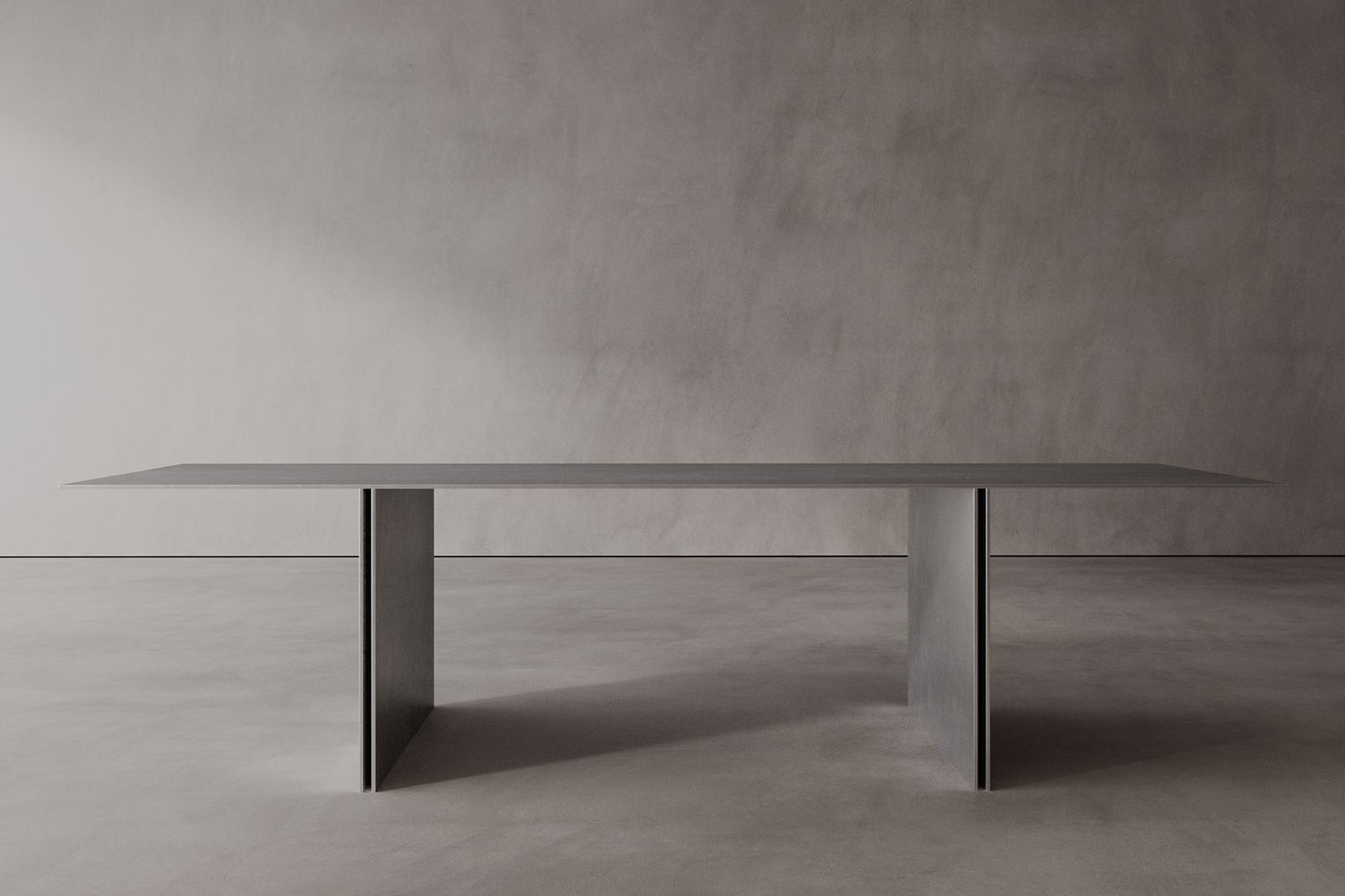 A sleek, modern stainless steel dining table with a minimalist design, featuring a rectangular shape and supported by a central pedestal column.