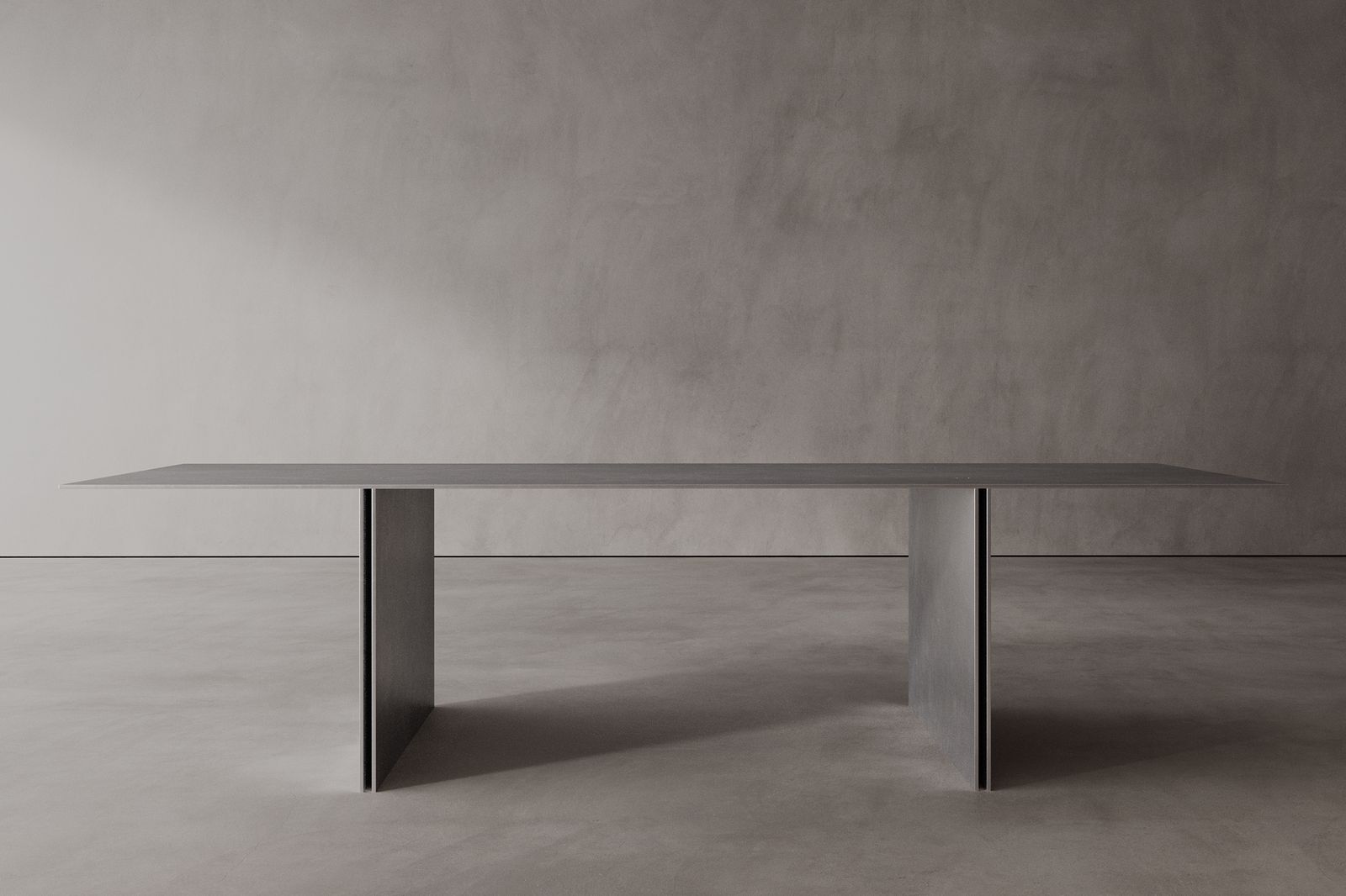 A sleek, modern stainless steel dining table with a minimalist design, featuring a rectangular shape and supported by a central pedestal column.