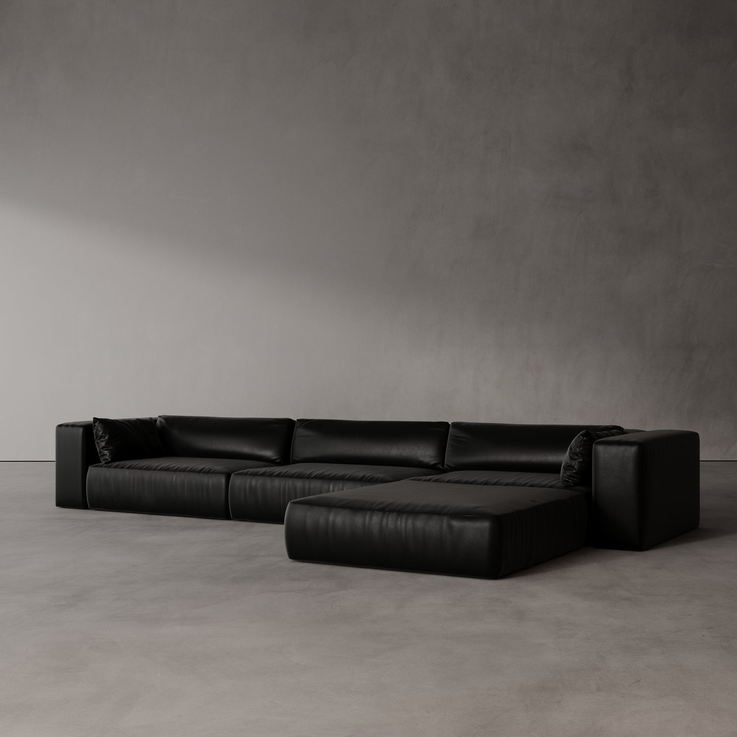 Black leather sectional sofa by antic studio against a plain wall