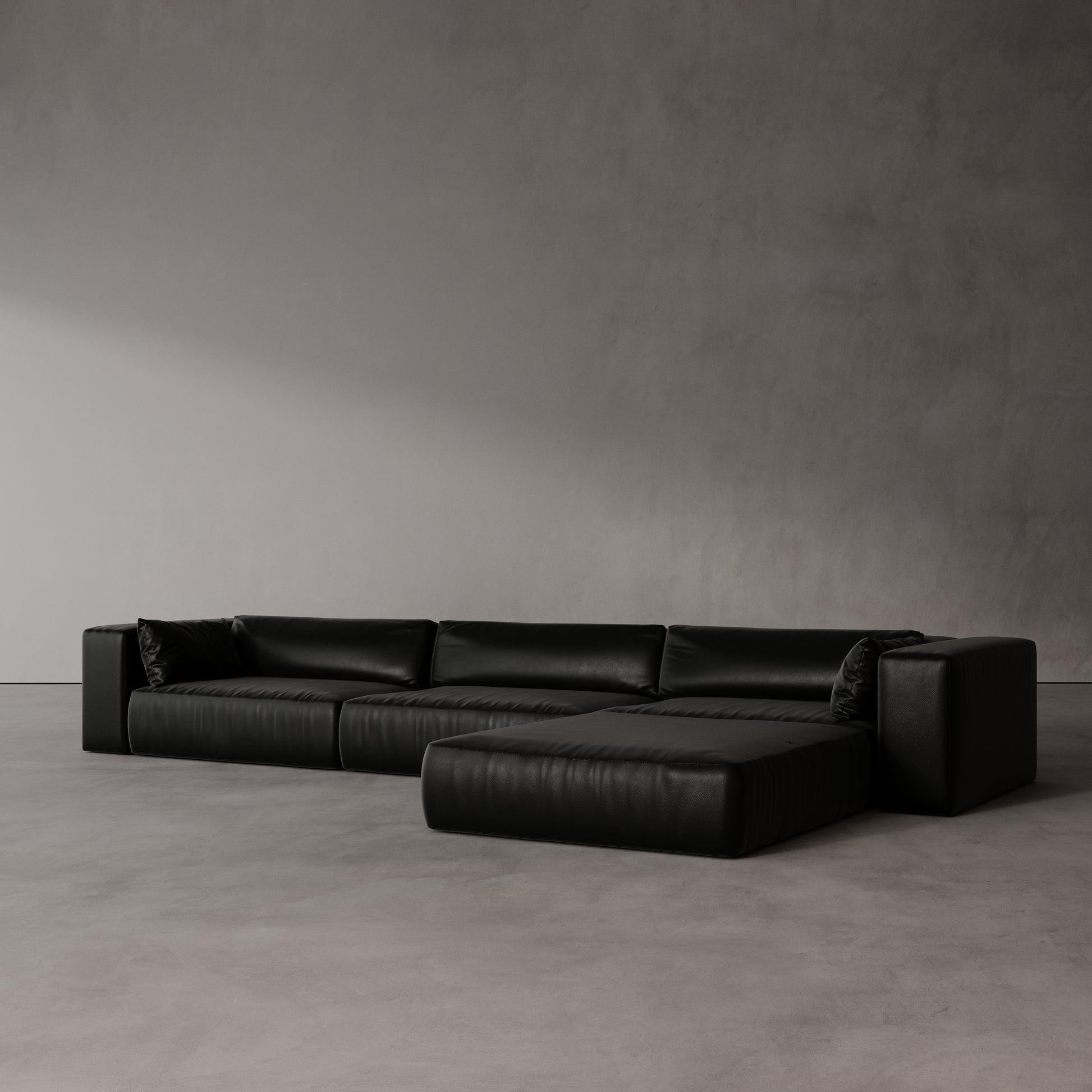 Black leather sectional sofa by antic studio against a plain wall