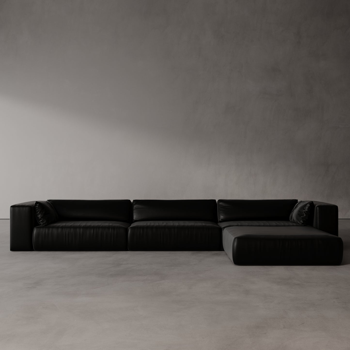 Black sectional sofa against a plain gray wall