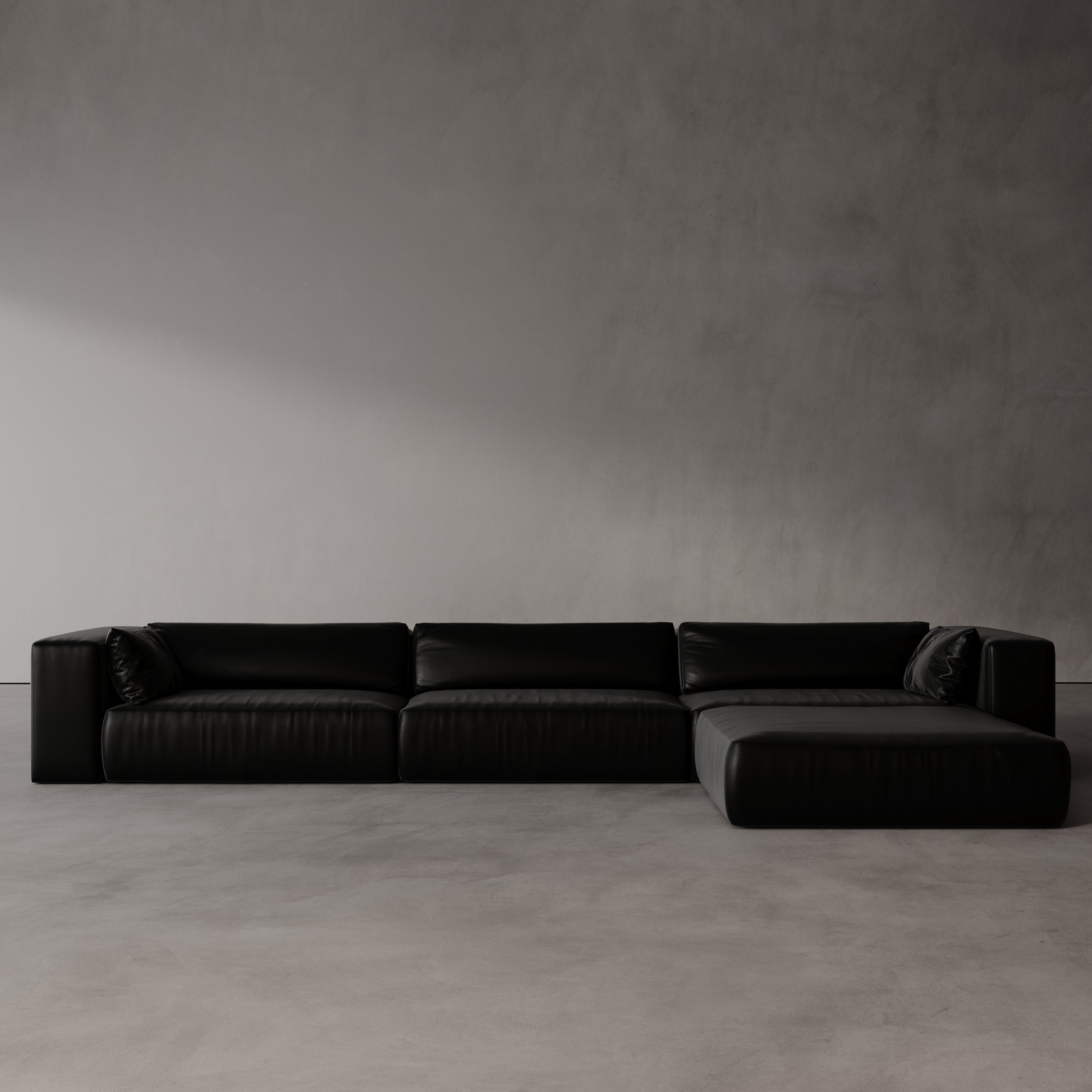 Black sectional sofa against a plain gray wall