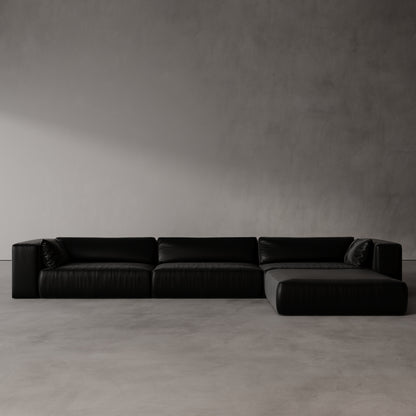 Black sectional sofa against a plain gray wall