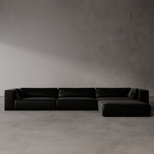 Black sectional sofa against a plain gray wall