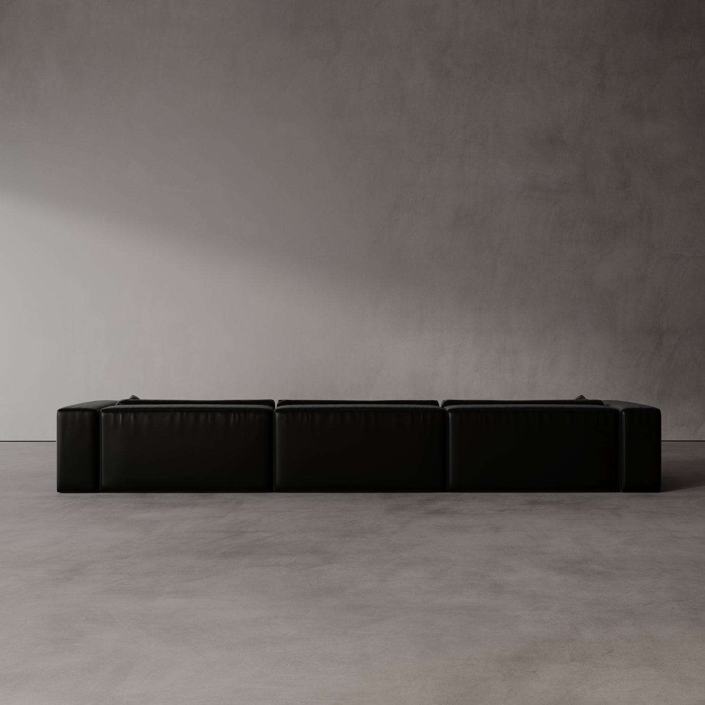 Black sectional sofa against a plain gray wall
