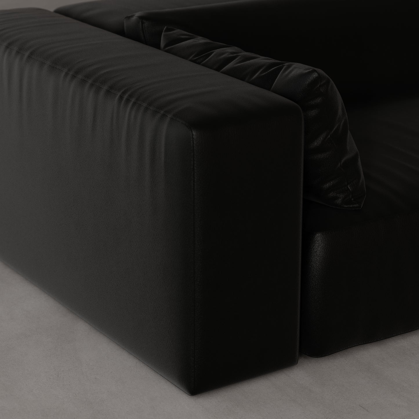 Black leather sofa on a gray floor by Antic Studio London