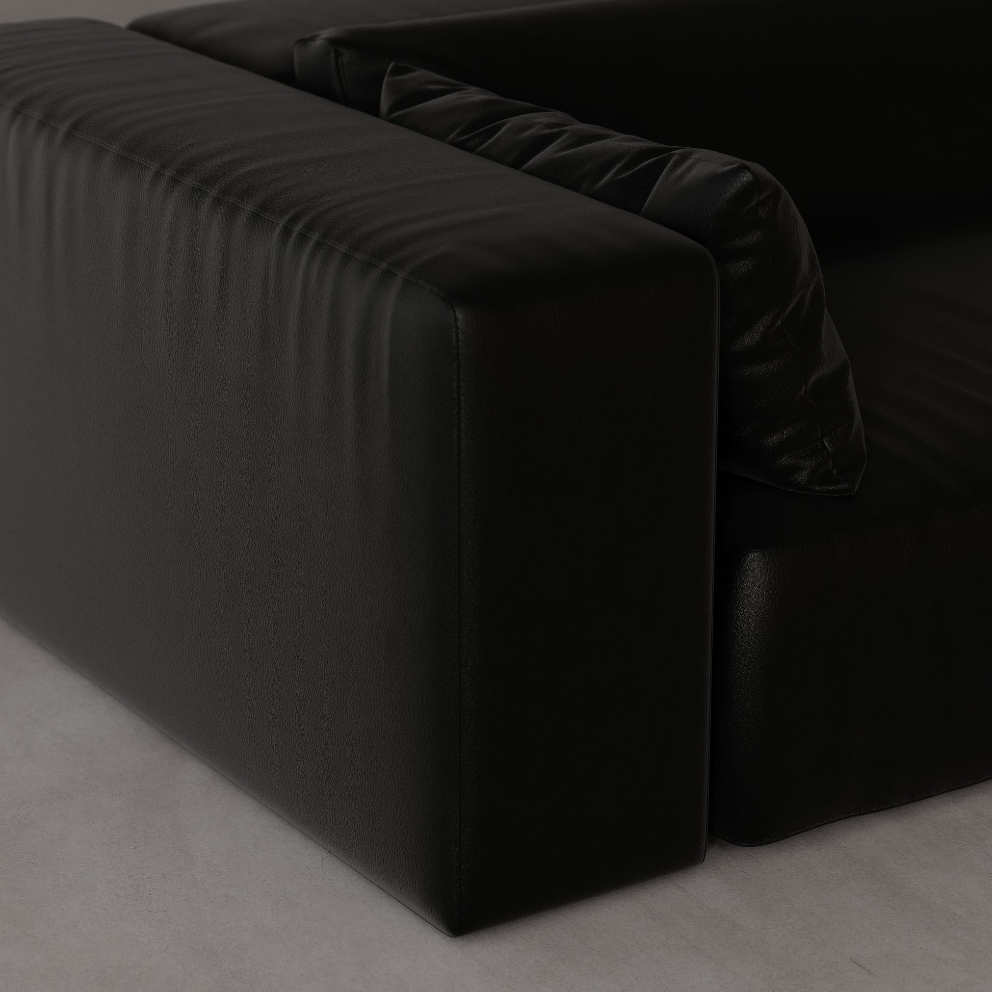 Black leather sofa on a gray floor by Antic Studio London
